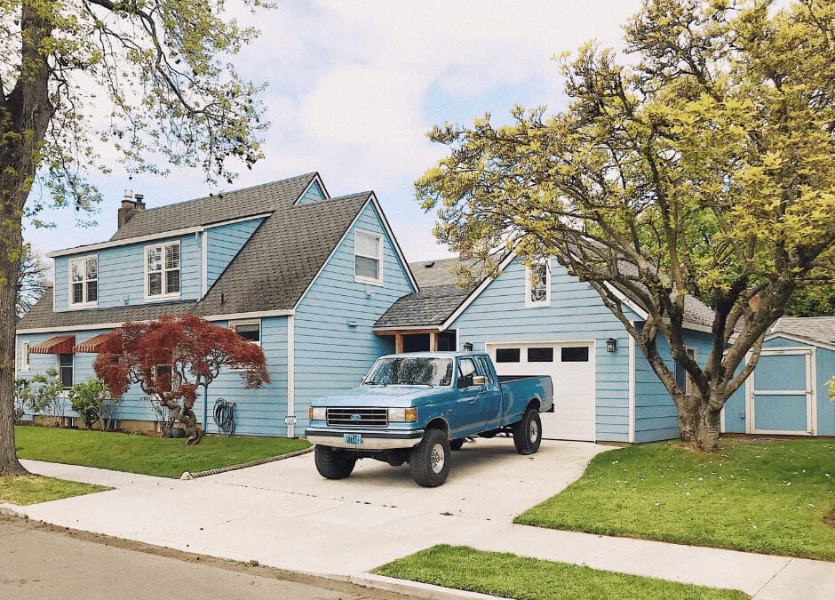 A concrete driveway with a blue truck parked in front of a blue house