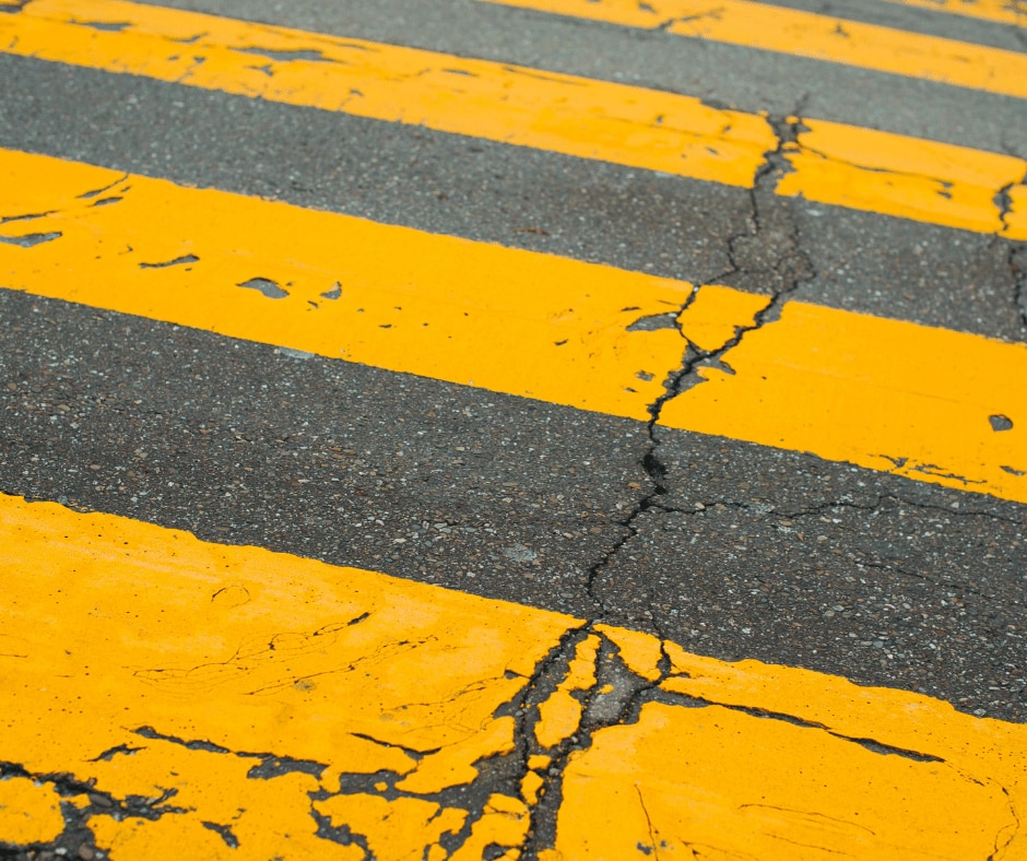 A damaged asphalt yellow crosswalk